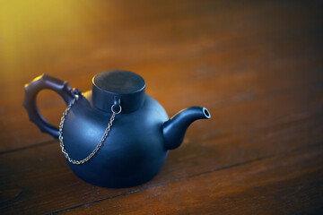 A black clay teapot on a wooden background.Chinese tea in a teapot.Tea brewing.