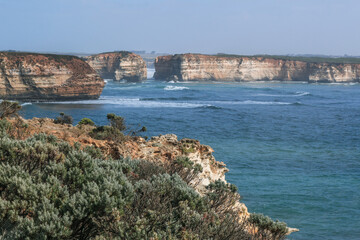 Great ocean road coast overlooking the Twelve Apostles Marine National Park - waves at sunset on the beach surrounded by big orange cliffs.