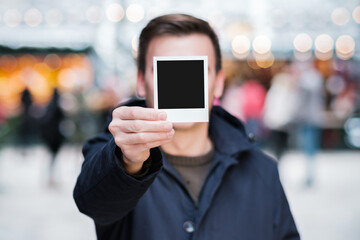 Fototapeta na wymiar junger Mann hält Polaroid Foto in der Hand