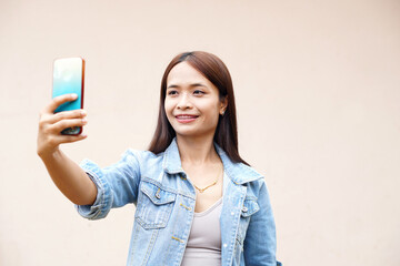 Fototapeta premium Asian woman happily takes a selfie with her phone.