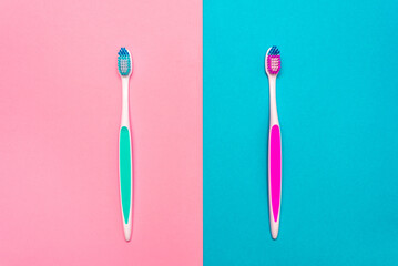 Close up of blue and pink plastic toothbrushes with pink and blue bristle on pink and blue background