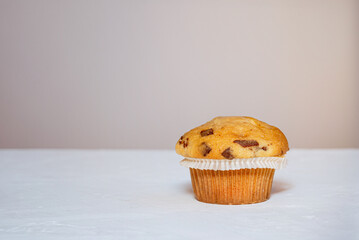 One muffin with chocolate peices on a white table