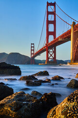 Sunset at Golden Gate Bridge on rock-covered beach with mussels