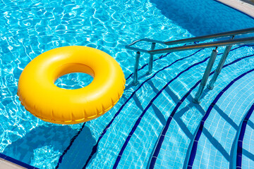 Yellow inflatable ring floating in swimming pool. Vacation concept with copy space