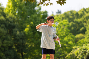 夏の公園でシャボン玉を遊んでいる小学生の女の子の様子