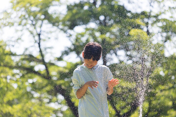 夏の公園で水遊びしている可愛い小学生の女の子の姿