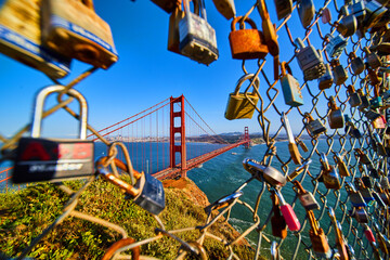 San Francisco iconic Golden Gate Bridge through opening in fence covered in locks