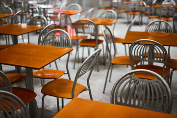 Wooden tables and chairs at large empty foodcourt in mall