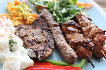 South African braai meat including lamb chops, boerewors sausage and chicken kebabs with potato salad, coleslaw and curry pasta salad 