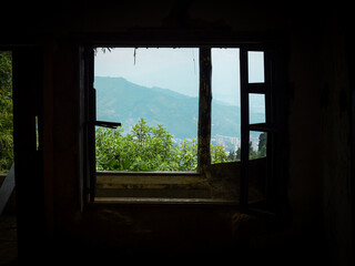 View of the Sky and Mountains from the Damp Weathered Window of an Abandoned House