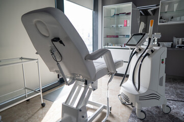 Empty beautician office with white couch and photorejuvenation machine. 