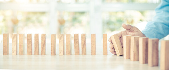 Close-up hand prevent wooden block not falling domino concepts of financial risk management and strategic planning and business challenge plan.