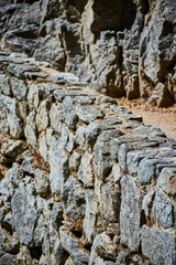Stone wall next to rocky cliffs and hiking path