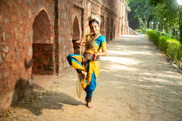 Indian woman Odissi dancer doing classical dance form outdoor at heritage place. Orissi dance. art...