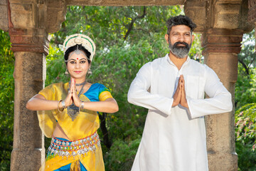 Indian woman Odissi dancer doing classical dance along with teacher or master outdoor. female do Orissi dance traning with coach. art and culture of india. namaste pose