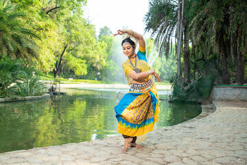 Indian woman Odissi dancer doing classical dance form outdoor at nature park. Orissi dance. art and...