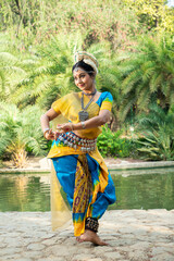 Indian woman Odissi dancer doing classical dance form outdoor at nature park. Orissi dance. art and...