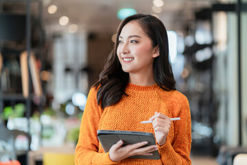 asian female smart entrepreneur walk working use tablet device stock manage and checking product inventory in furniture showroom,asian woman smiling cheerful business owner work in furniture store