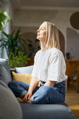 Adult woman sitting on the couch with closed eyes. Mindfulness concept