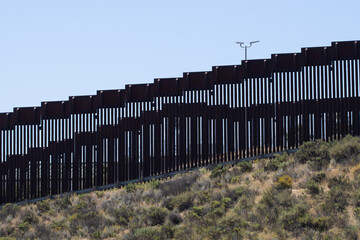 A double vertical border wall between the United States and Mexico, separating San Diego and Tijuana, viewed from the Border Field State Park in San Diego, California.