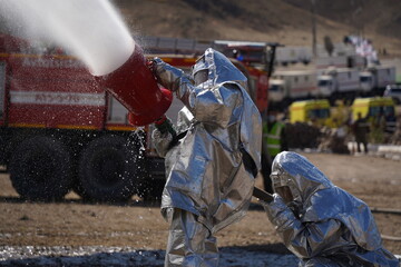 Fototapeta na wymiar Almaty, Kazakhstan - 09.22.2021 : Rescuers in special protective suits extinguish the plane in training
