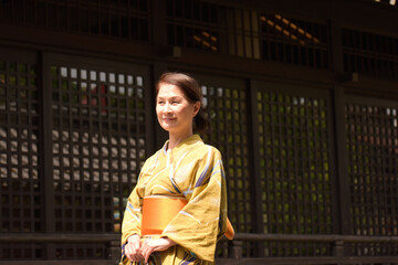 日本家屋の前で和服でたたずむシニア女性