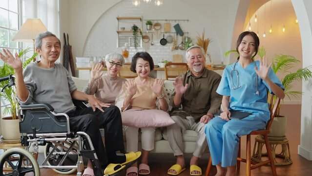 portrait of asian senior male female friend group sit of sofa smiling together in nursing home senior daycare with young nurse care giver in uniform look at camera group shot in living room cheerful