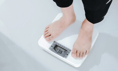 Feet standing on the analog weight scale. Household object. Weight control and obesity prevention...