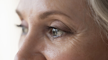 Middle-aged attractive woman looks into distance, cropped close up upper face view. Eyesight,...