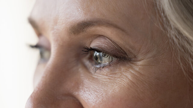 Middle-aged attractive woman looks into distance, cropped close up upper face view. Eyesight, vision care, ophthalmology clinic advertisement for older, eye-care, disease prevention, treatment concept