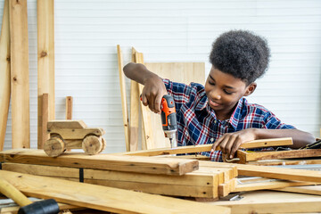 Portrait of african american little child wearing shirt with a drill in hands and help dad assembling furniture shelf with power screwdriver tool, learning concept.