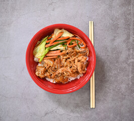 Korean beef pork rice and sauteed scallions, carrots, collard greens, topped with sesame seeds served in a red bowl. top view.