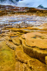 Snowy hot spring terraces in Yellowstone with steam