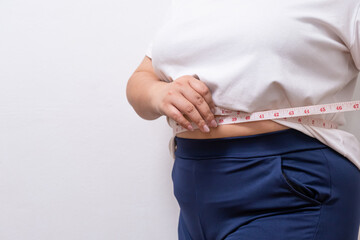Close up shot at hand of women while use measure tape with her tummy or waist belly of chubby women that show sign of overweight. On white background with copy space for text