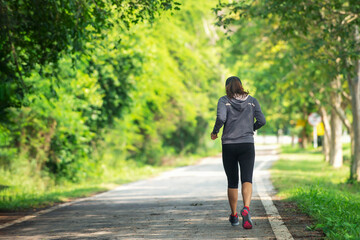 Asian  woman in sportswear Jogging running  at park in sunshine beautiful  day