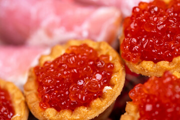 Salmon caviar in a tartlet on a glass dish. Festive table setting