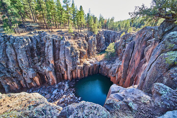Large rocky canyon with pool of water and small waterfall