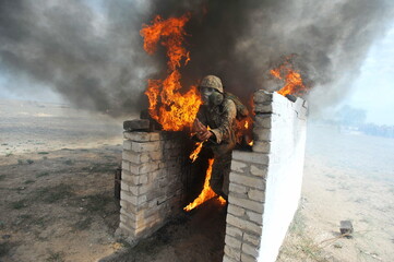 Almaty, Kazakhstan - 08.22.2012 : Soldiers pass a burning obstacle course in gas masks.