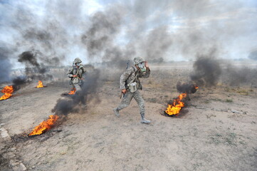 Almaty, Kazakhstan - 08.22.2012 : Soldiers pass a burning obstacle course in gas masks.