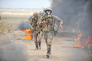 Almaty, Kazakhstan - 08.22.2012 : Soldiers pass a burning obstacle course in gas masks.