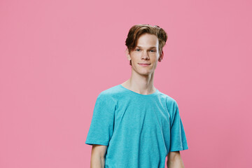horizontal photo of a young man on a pink background in a blue t-shirt