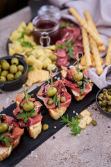 bruschetta with prosciutto ham and capers with traditional antipasto meat plate on background