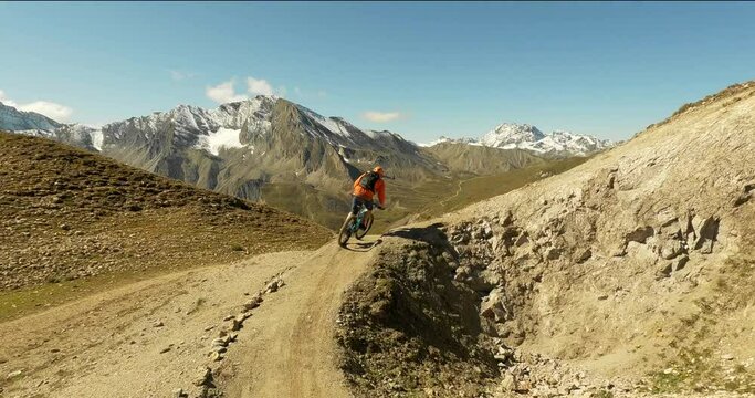 Young downhill mountain biker riding on a single trail with a modern trailbike in the austrian alps. Fun mountain biking in amazing landscape in high alpine mountain terrain with a bicycle. 4K 3fps