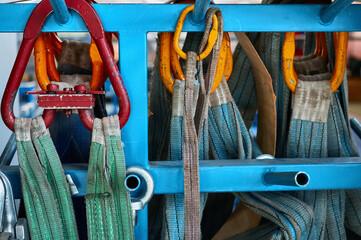 Rigging equipment with strops hangs on rack in warehouse