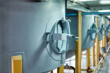 Side hatches with walls of metal tanks for making alcohol drinks in light workshop