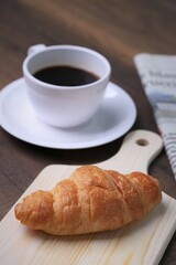 Breakfast consists of croissants, with hot fading and newspapers in the background.