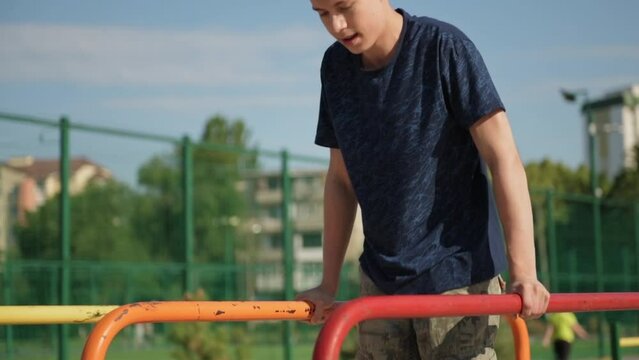a teenage boy trains on a sports ground outdoors, he does physical exercises, a healthy lifestyle, a bright sunny day in summer