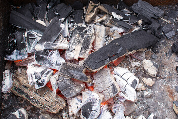Barbecue grill with glowing and flaming hot charcoal briquettes, close-up