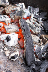 Barbecue grill with glowing and flaming hot charcoal briquettes, close-up