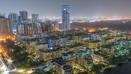 Obraz premium Skyscrapers in Barsha Heights district and low rise buildings in Greens district aerial night timelapse.